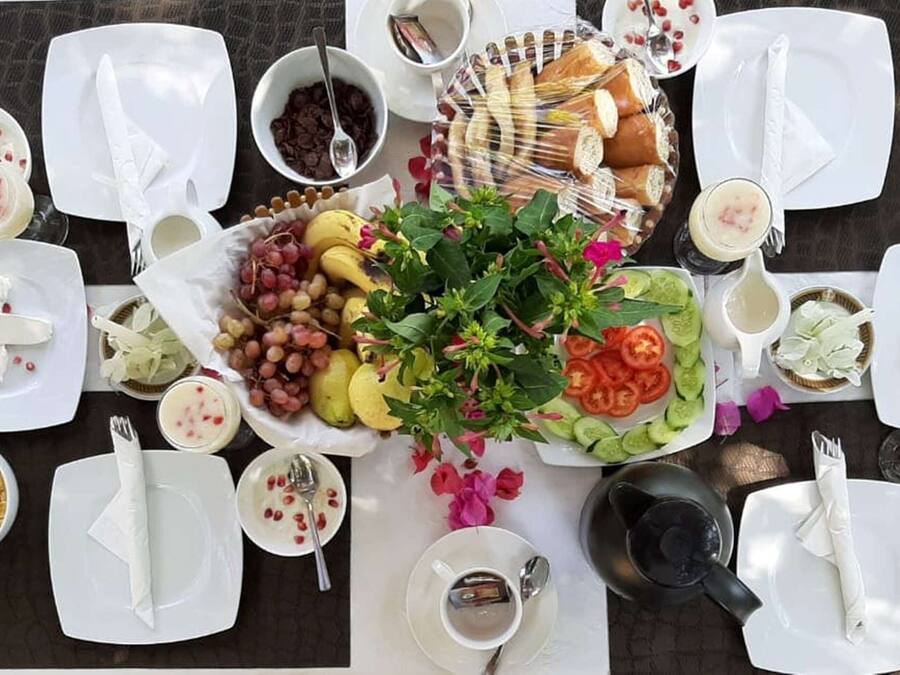 A table set for a meal with various dishes, including fruits, bread, and desserts.