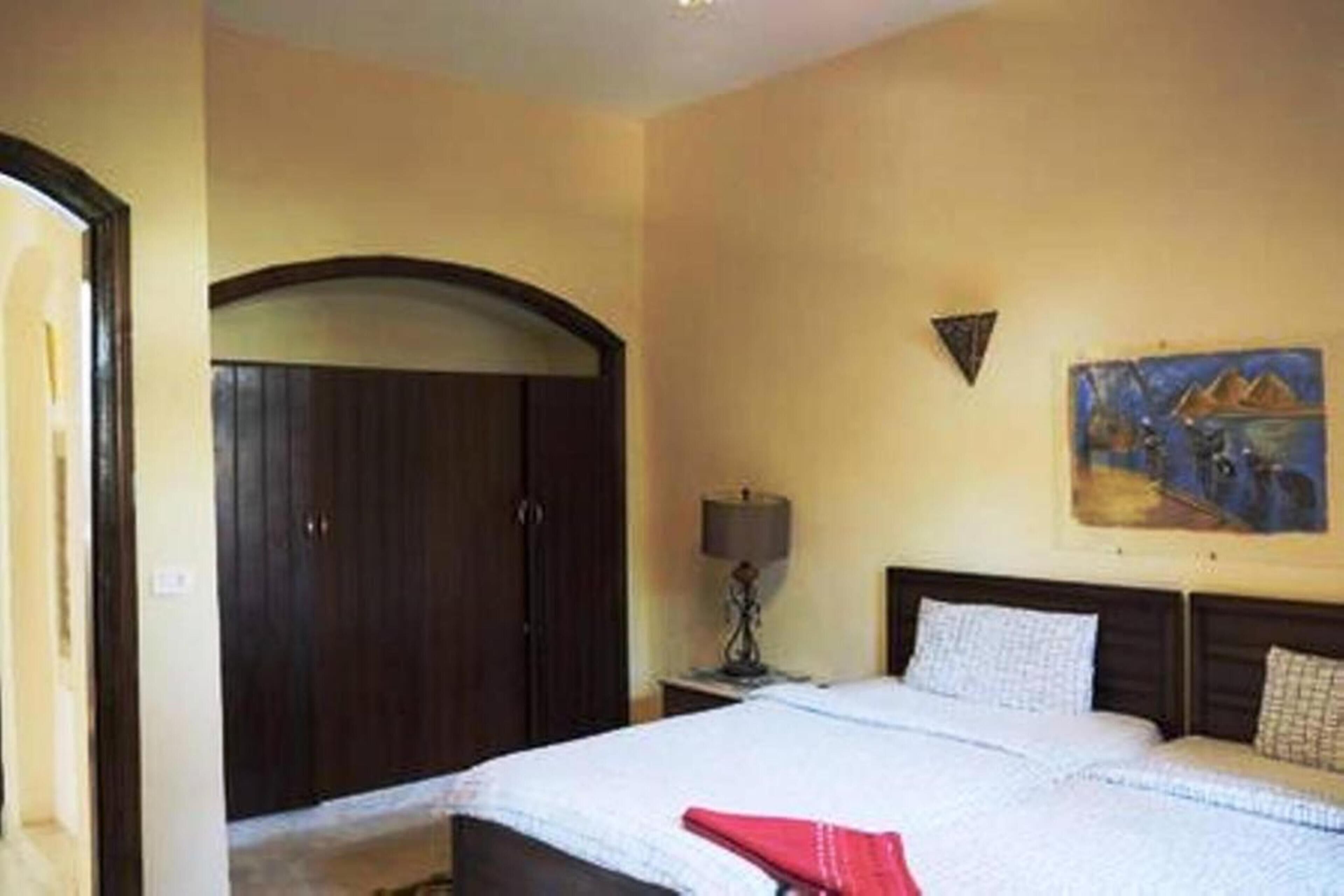 Un dormitorio con una cama, una mesita de noche, una lámpara, un cuadro y un armario.