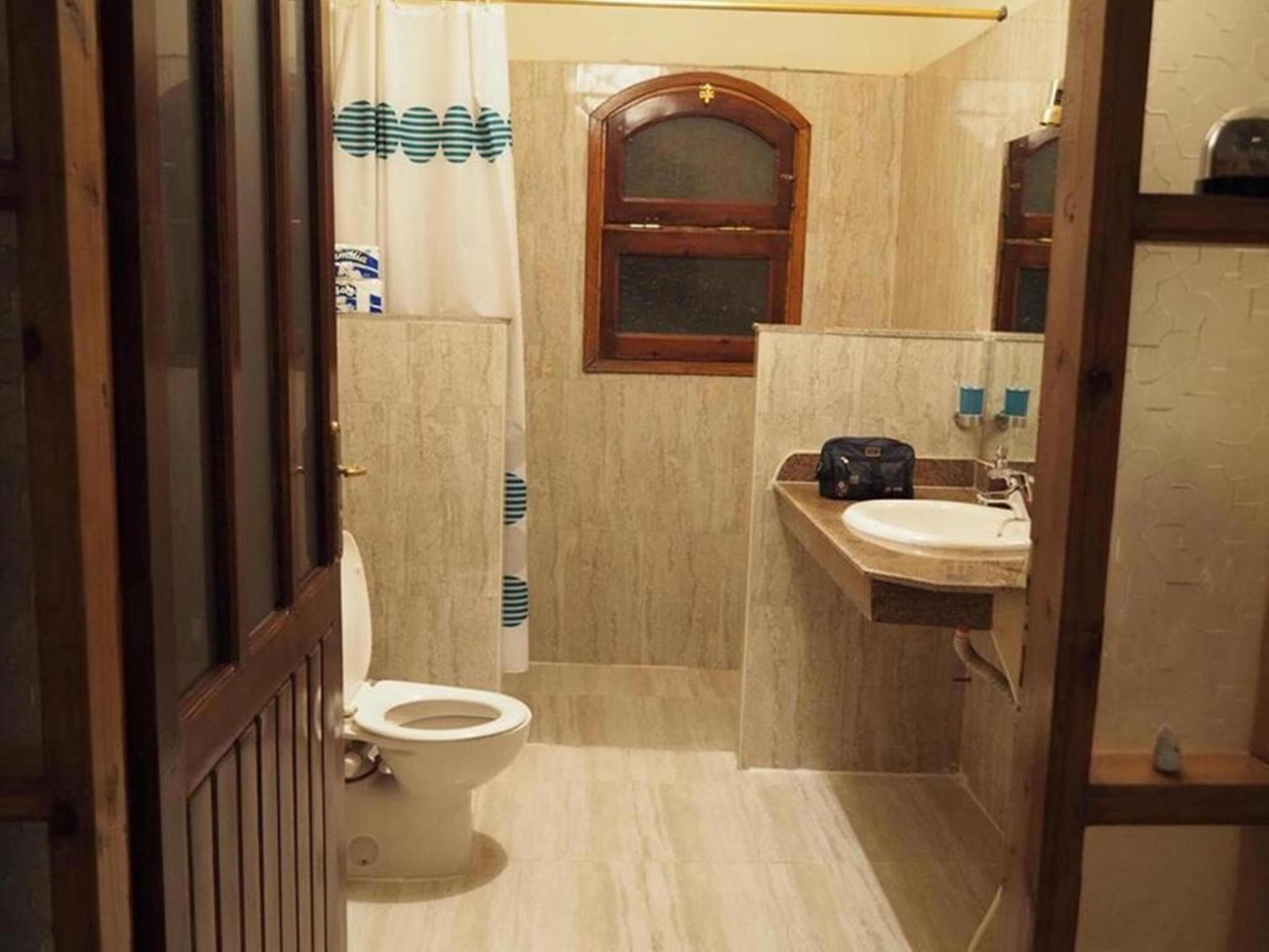 A compact bathroom with a toilet, a sink, and a shower curtain.
