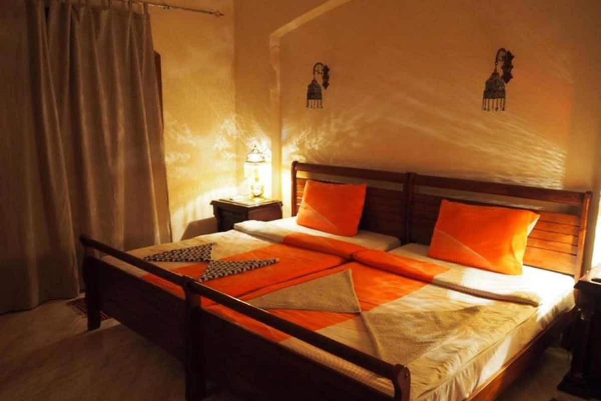 A bed with a wooden frame, orange bedding, and a nightstand with a lamp.