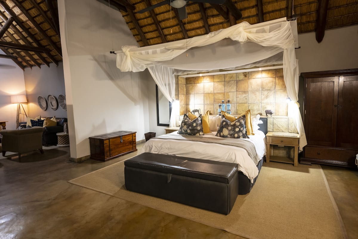 Une chambre à coucher avec un lit à baldaquin, une commode en bois, une table de chevet et une armoire.