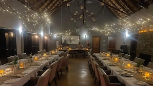 A long dining table set with candles, chairs, and a chandelier.