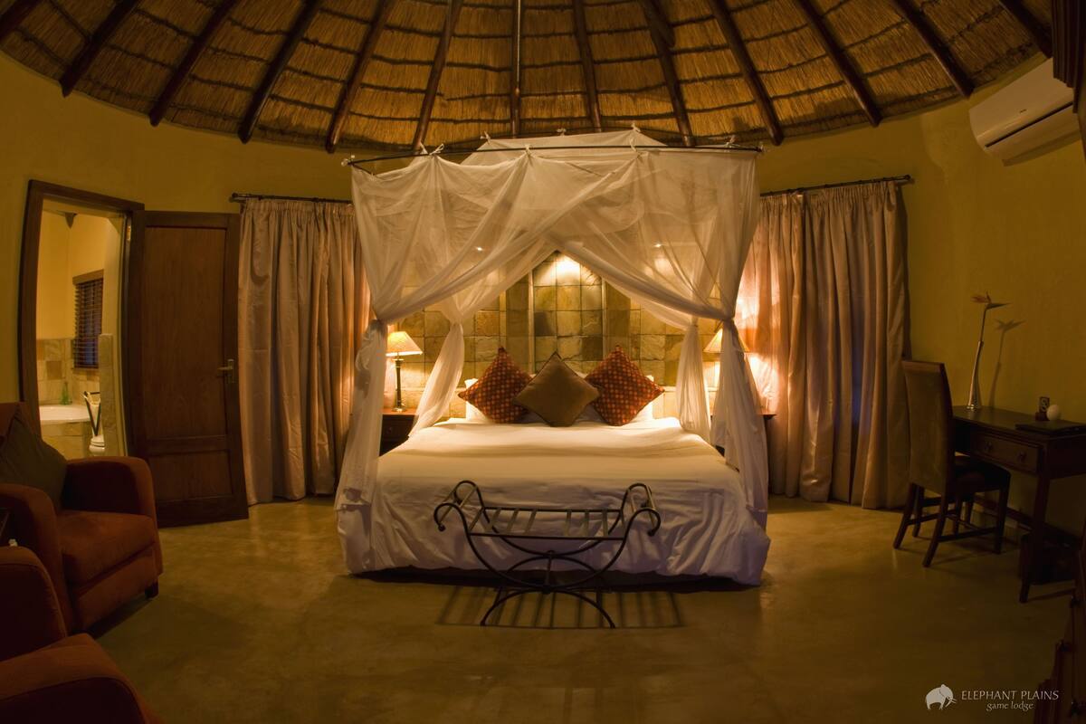 Une chambre à coucher avec un lit à baldaquin, un bureau, une chaise et une petite table.