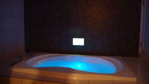 A modern bathroom with a freestanding bathtub, a built-in control panel, and a tiled floor. - Hotel Mint - Adults Only (Ikeda)