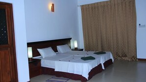 A hotel room with a large bed, two bedside tables, and a curtain.