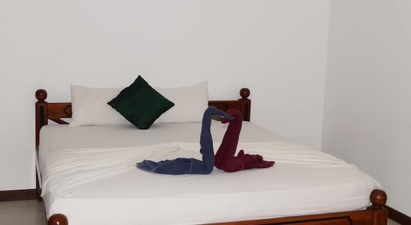 Un lit avec un drap blanc, un oreiller vert et deux serviettes disposées en forme de cygne.