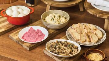 A wooden table with various food items including eggs, ham, mushrooms, and bread.