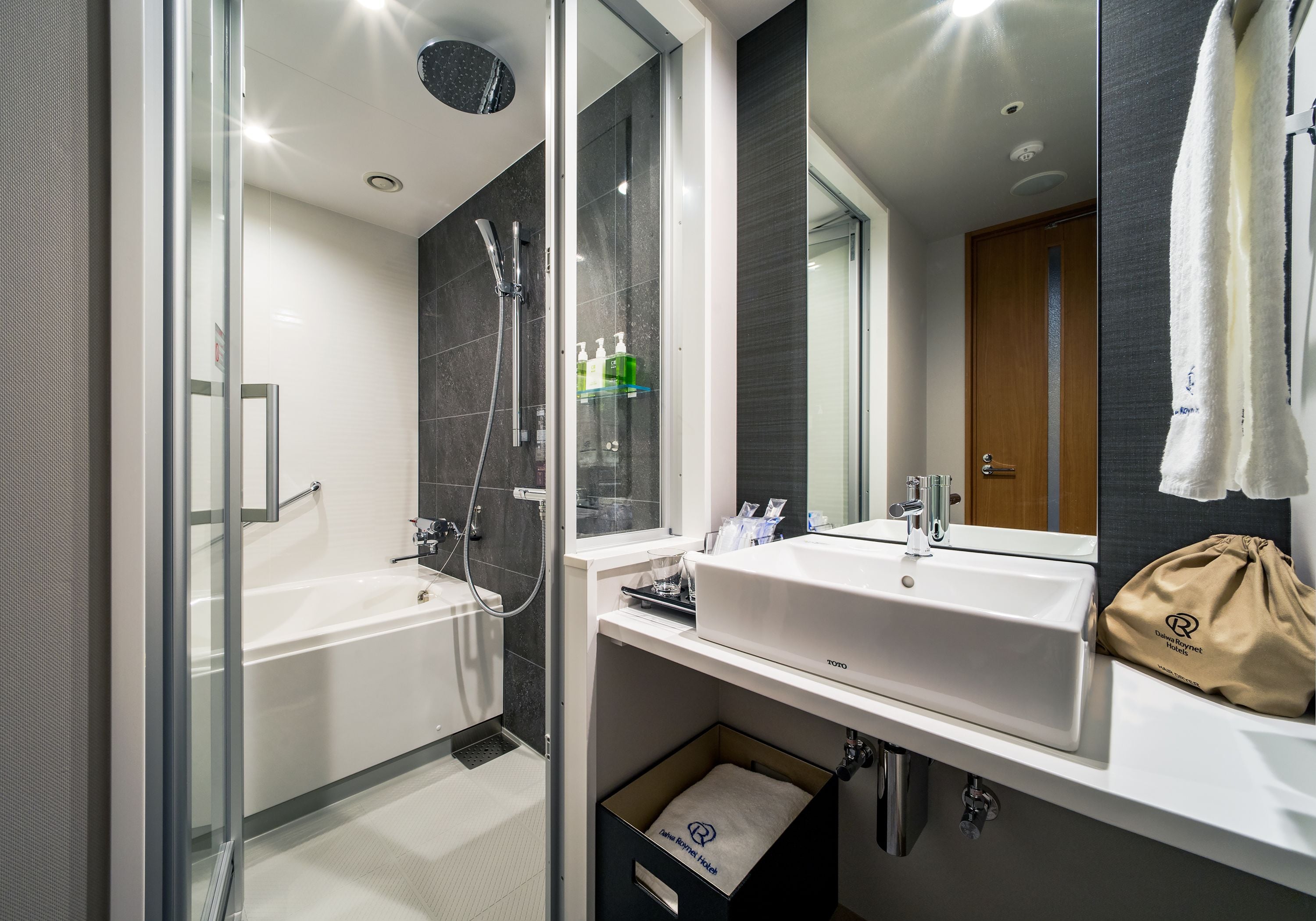 A modern bathroom with a glass-enclosed shower, a white bathtub, and a vanity with a mirror.