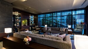 A modern hotel lobby with a large sectional sofa, a reception desk, and a large window offering a city view. - Daiwa Roynet Hotel Nagoya Taiko dori Side (Nagoya)