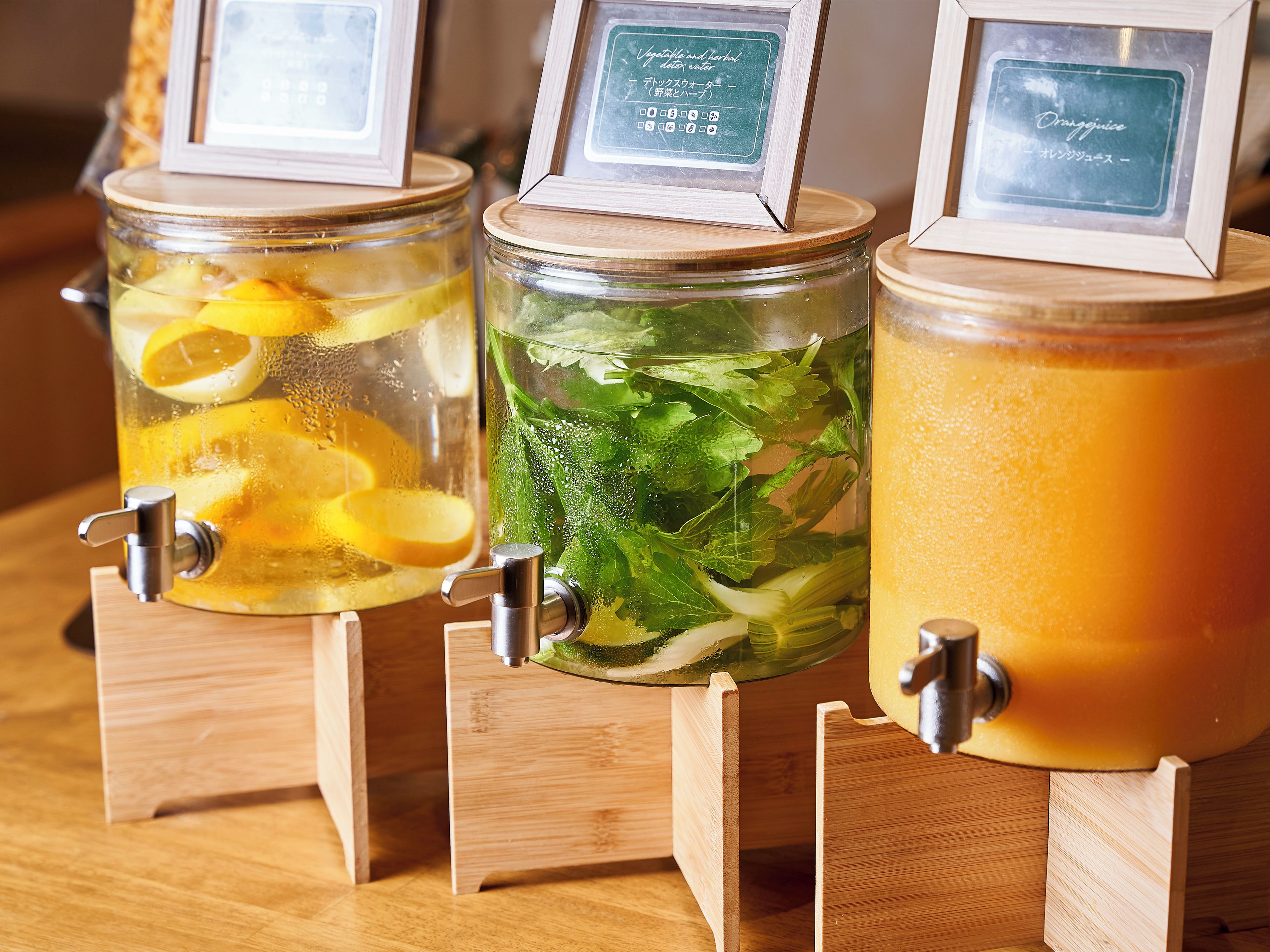 Tres dispensadores de madera con diferentes bebidas, cada uno con una etiqueta.
