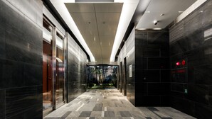 A modern hallway with dark tiled walls, a patterned floor, and recessed lighting. - Daiwa Roynet Hotel Nagoya Taiko dori Side (Nagoya)