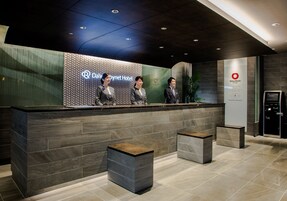 A reception area with a modern design, featuring a reception desk, two waiting areas, and a digital information kiosk.