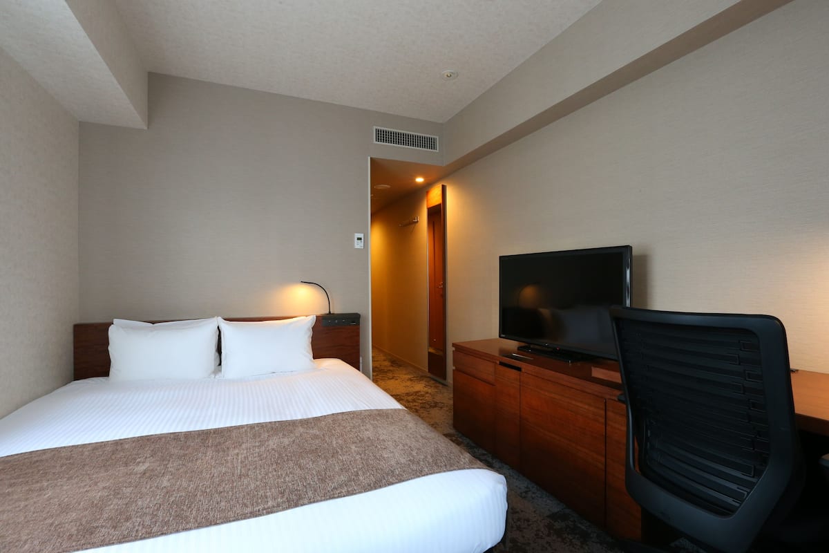 Une chambre d’hôtel avec un grand lit, une télévision, un bureau et une chaise.