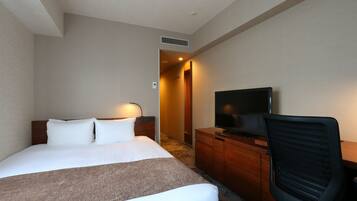 A hotel room with a large bed, a TV, a desk, and a chair.