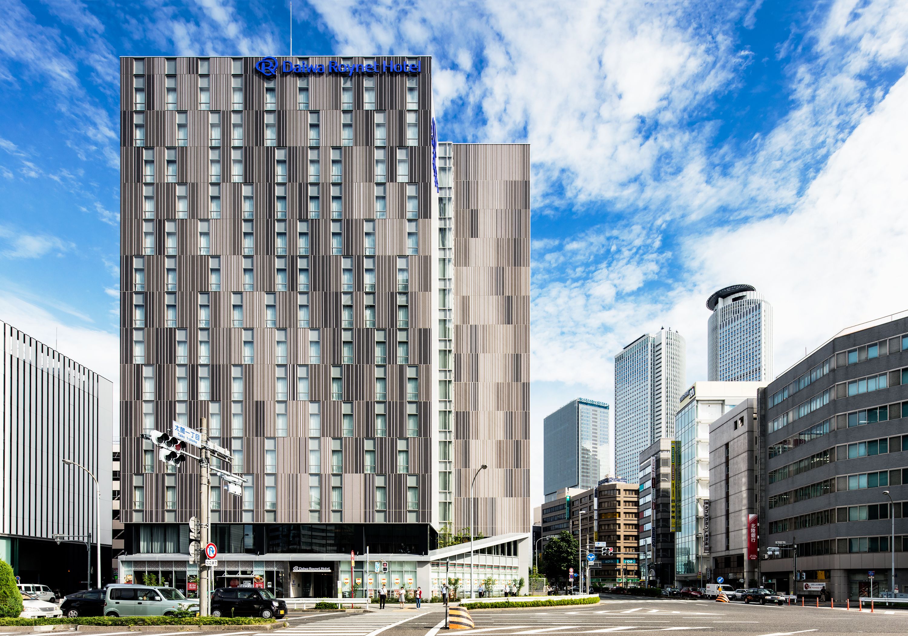 Un hotel moderno con fachada vertical, varios pisos y un letrero llamativo en la parte superior.