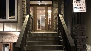 A staircase leading to a building entrance with a sign reading "Furano Fresh Powder rtments." - Furano Fresh Powder Apartments and Chalet (Furano)