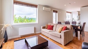 A modern living room with a beige sofa, a coffee table, and a dining area with a table and chairs. - Furano Fresh Powder Apartments and Chalet (Furano)