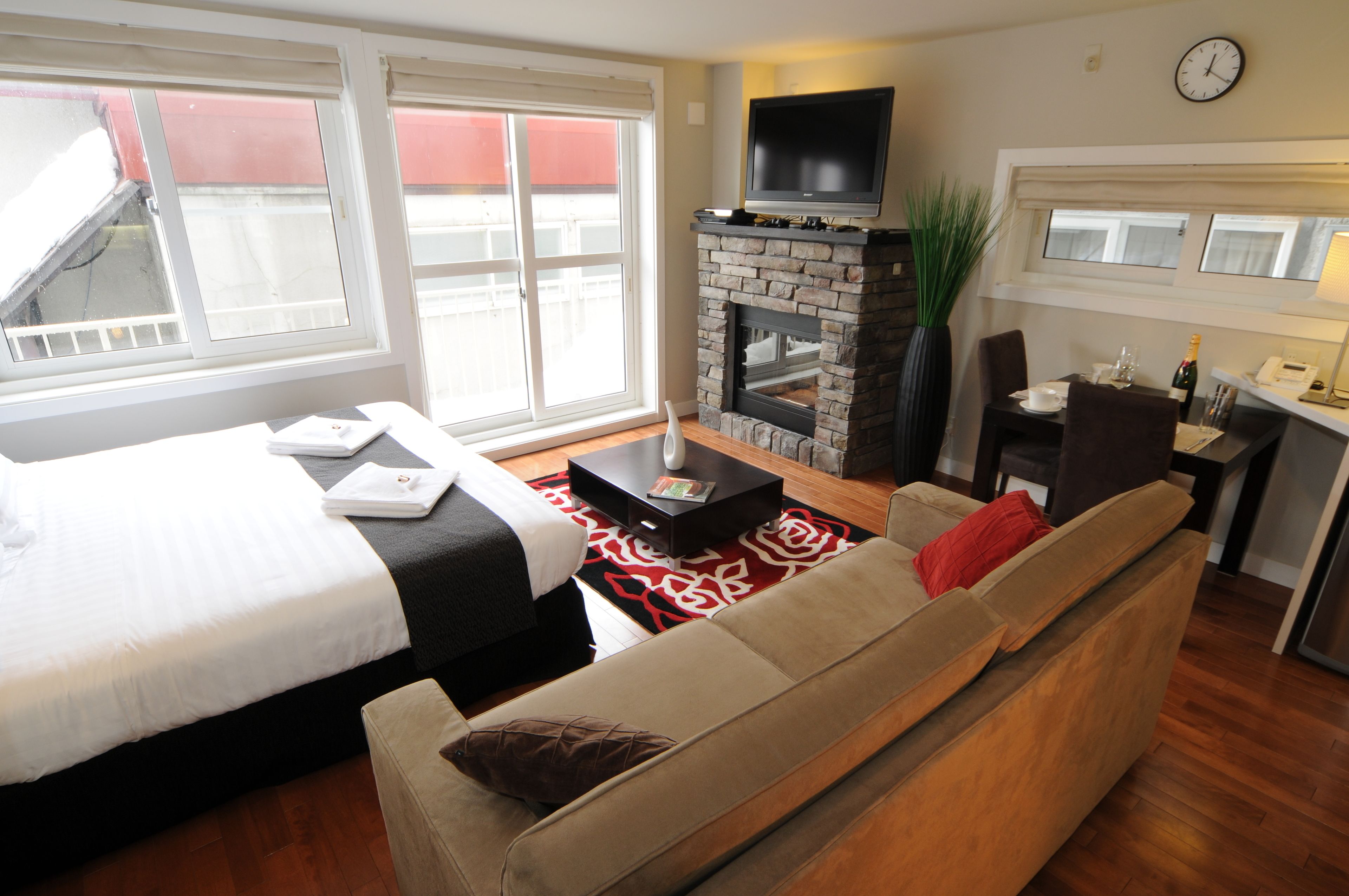 Una habitación de hotel con cama, sofá, chimenea, televisión y un área de comedor con mesa y sillas.