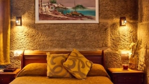 Una camera da letto con una parete in pietra rustica, un quadro raffigurante una scena costiera e due abat-jour.