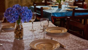 Una tavola imbandita con piatti, bicchieri da vino e un vaso con fiori blu.