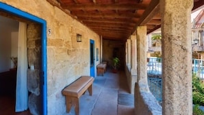 Un edificio in pietra con un portico coperto, una panchina e una porta con cornice blu.