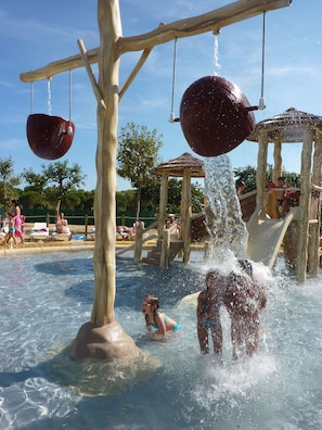 A water park with a play structure, slides, and a pool area.