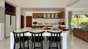 Una cocina moderna con una isla central, armarios de madera y una zona de comedor con tres taburetes.