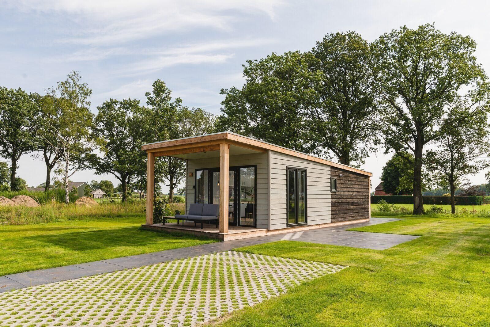 Una estructura moderna al aire libre con un área de estar cubierta, un patio y un césped.