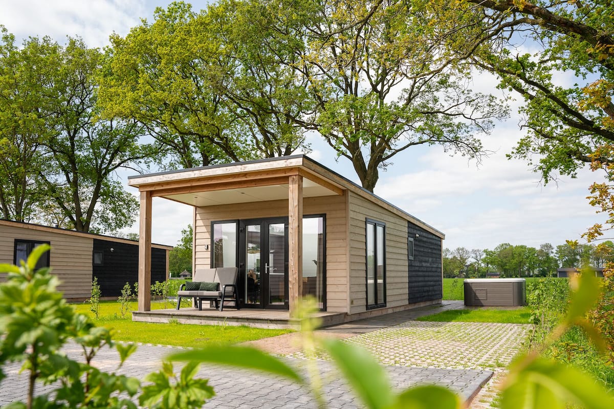 A modern, single-story house with a covered patio, large windows, and a well-maintained garden.