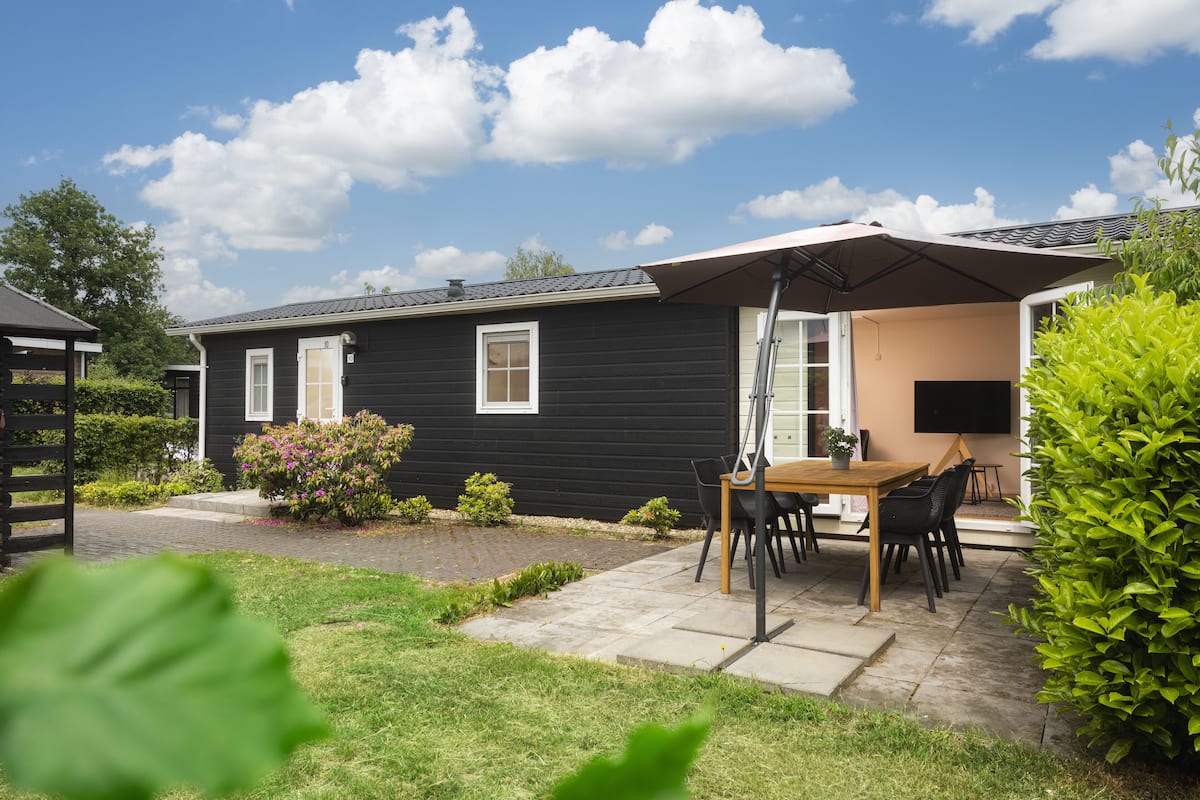 A black house with a patio, a wooden table, and chairs.