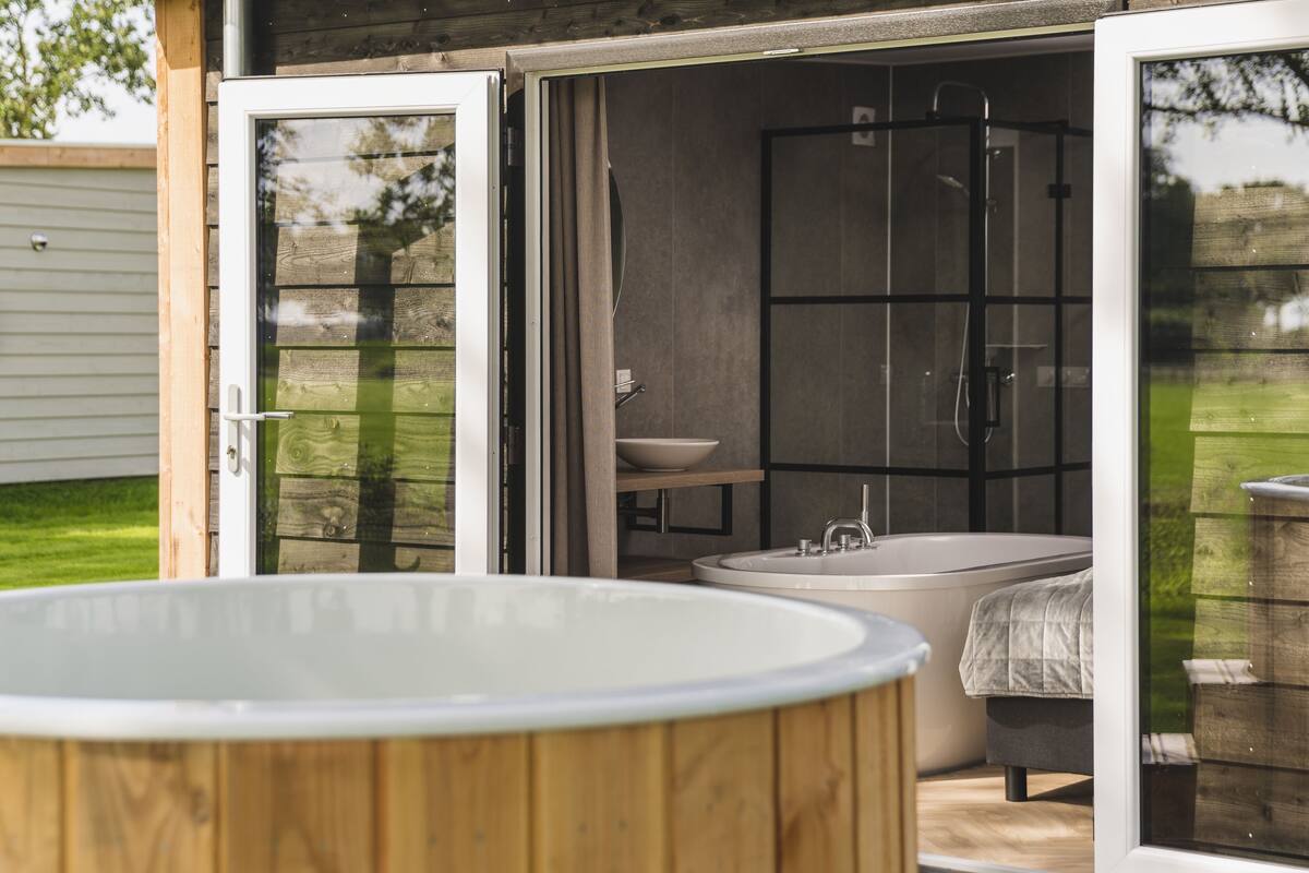 An outdoor hot tub and a walk-in shower with a large window.