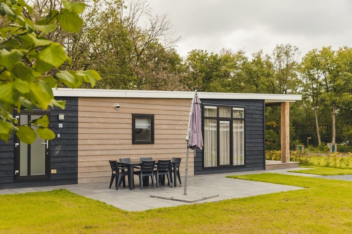 A modern house with a patio, a dining table, and chairs.