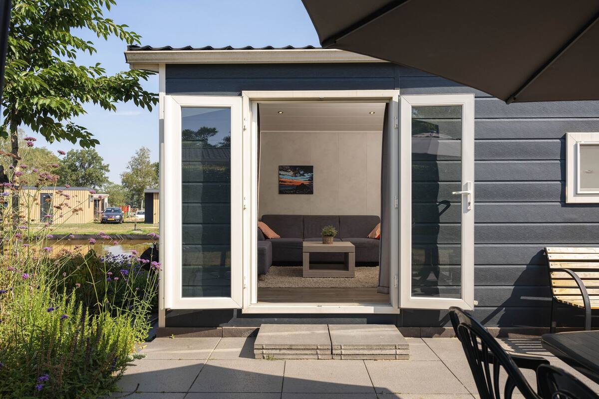 A modern house with a sliding glass door leading to a patio area with a sofa and a small table.