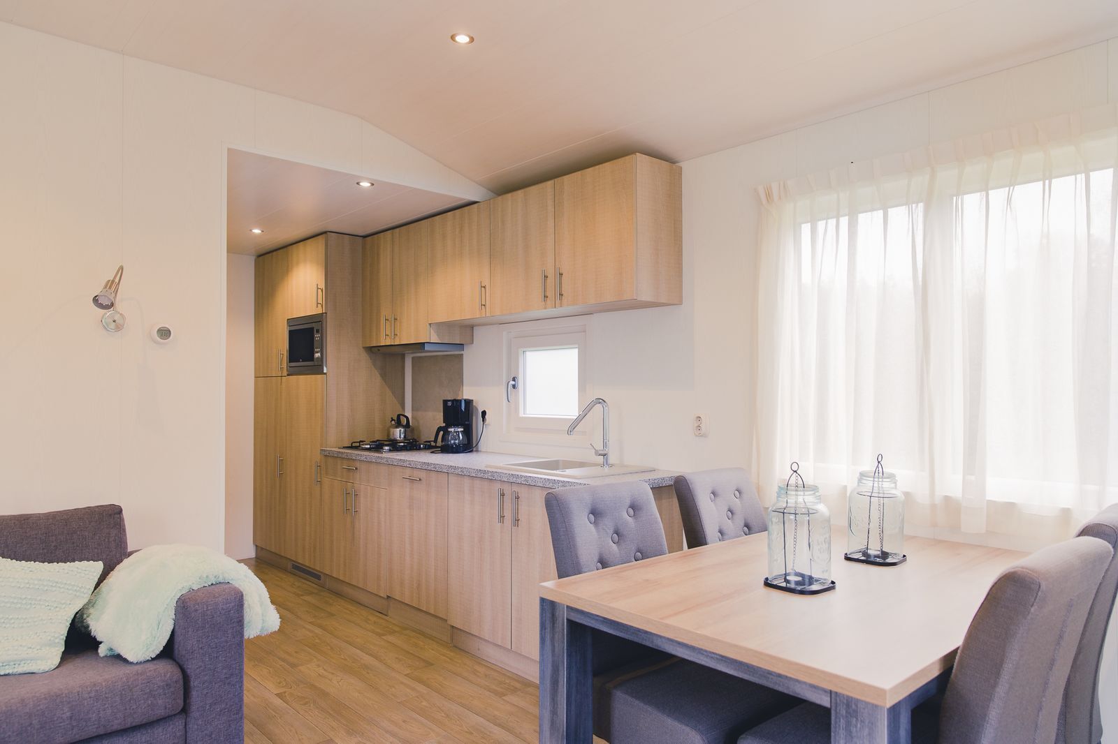 A compact kitchen with wooden cabinets, a built-in stove, and a dining area with a table and chairs.