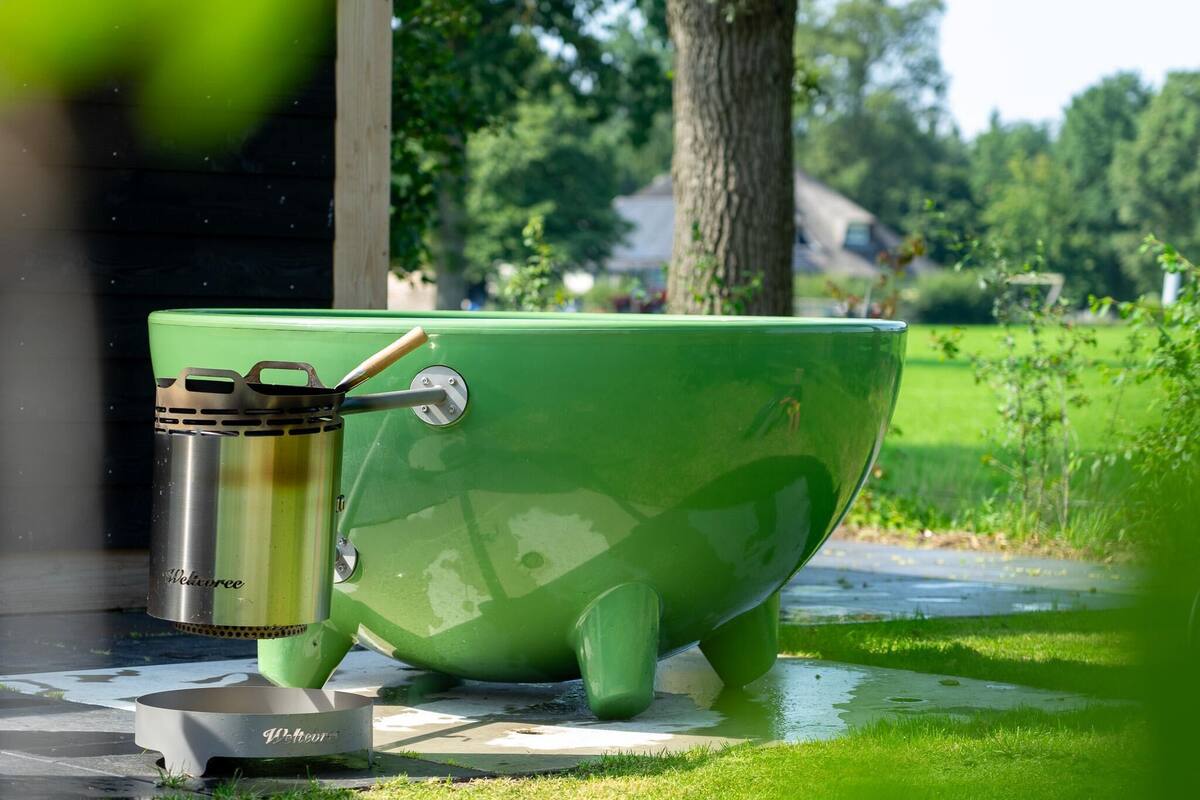 A green outdoor cooking setup with a kettle and a pot, placed on a tiled surface.