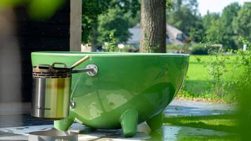 A green outdoor cooking setup with a kettle and a pot, placed on a tiled surface.