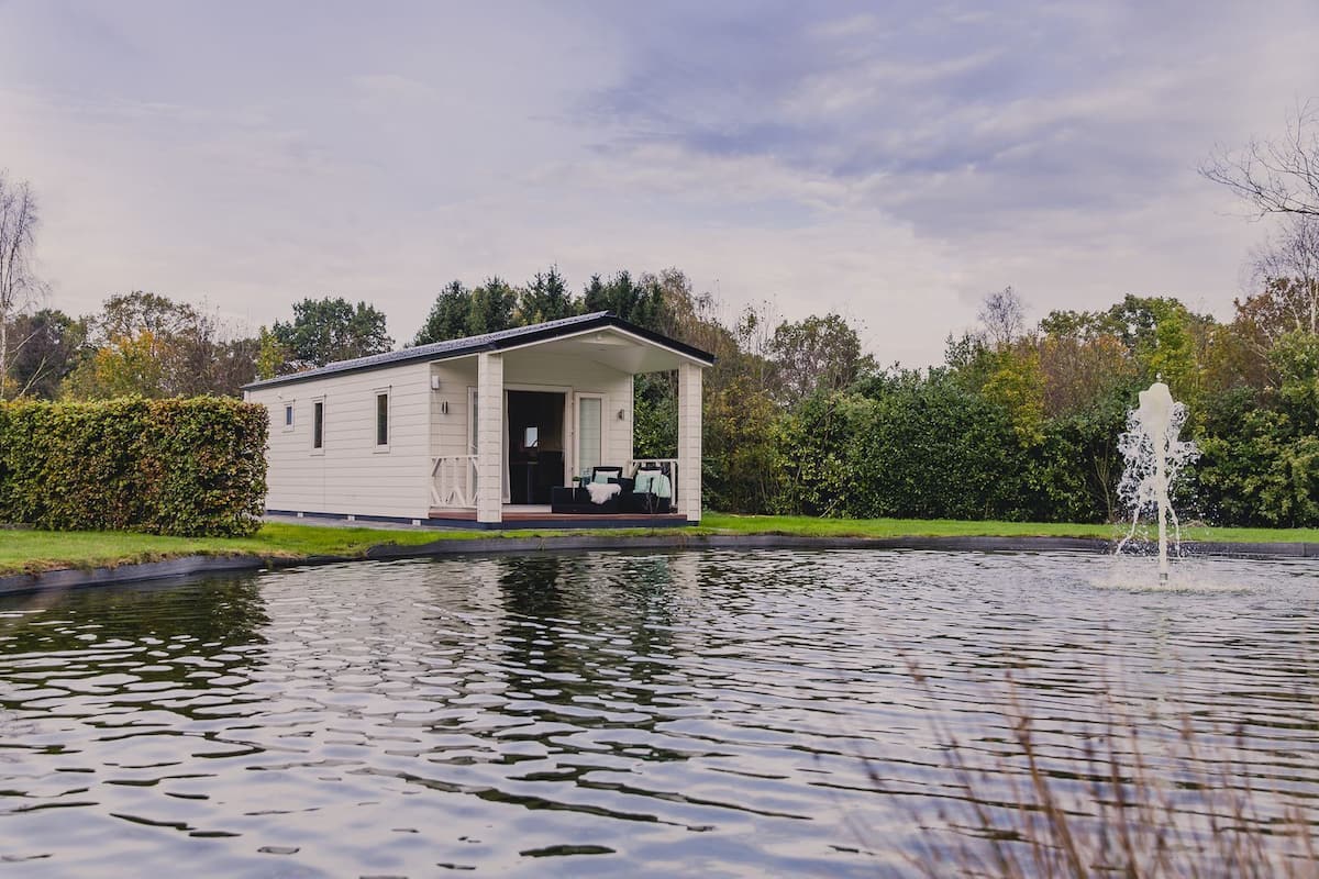 A white mobile home with a covered porch and a small garden area.