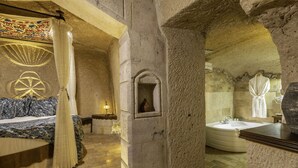 Ein Badezimmer mit Steinwänden, einer Badewanne, einer kleinen Nische mit Spiegel und einem Himmelbett.