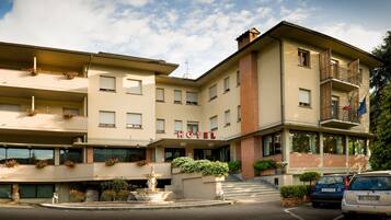 Hotel entrance with a welcoming atmosphere, featuring a prominent sign and flower-adorned balconies.