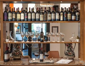 A wine bar with shelves of wine bottles and glasses. - Hotel Ristorante Milano (Borgo a Mozzano)
