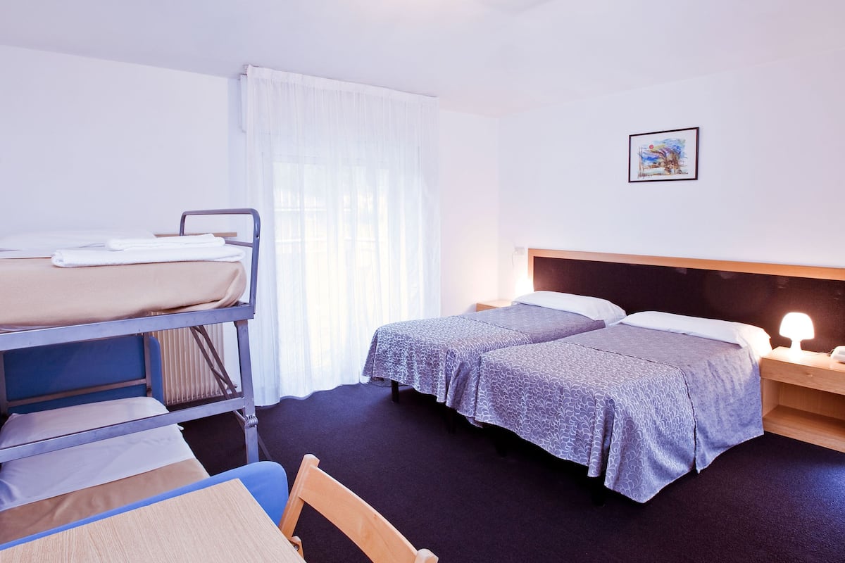A room with a bunk bed, a single bed, a desk, and a chair.