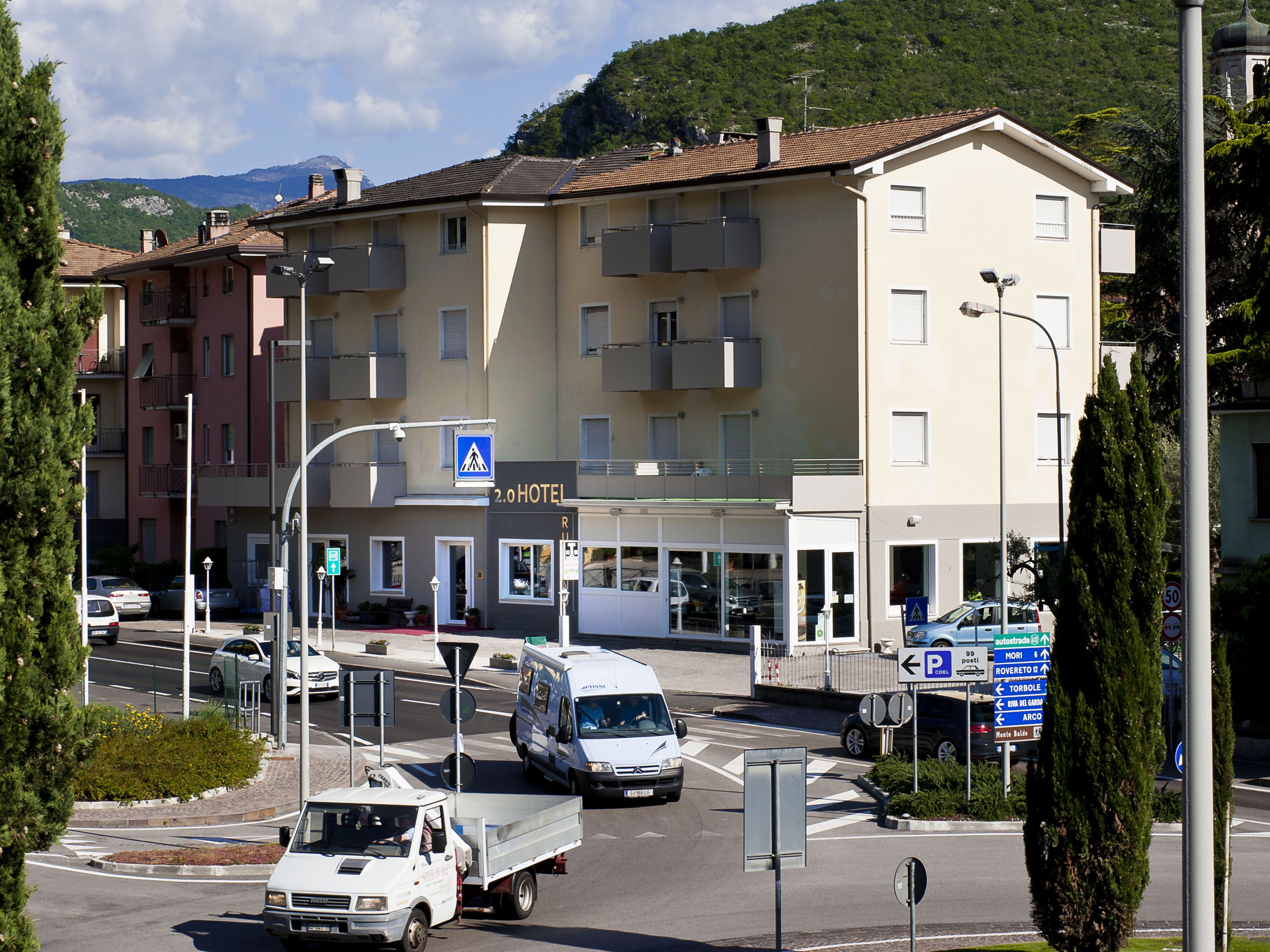 Un hotel con un cartello che indica una classificazione a due stelle, un’area di parcheggio e una strada con veicoli.