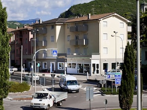 A hotel with a sign indicating it is a 2-star establishment, a parking area, and a street with vehicles.