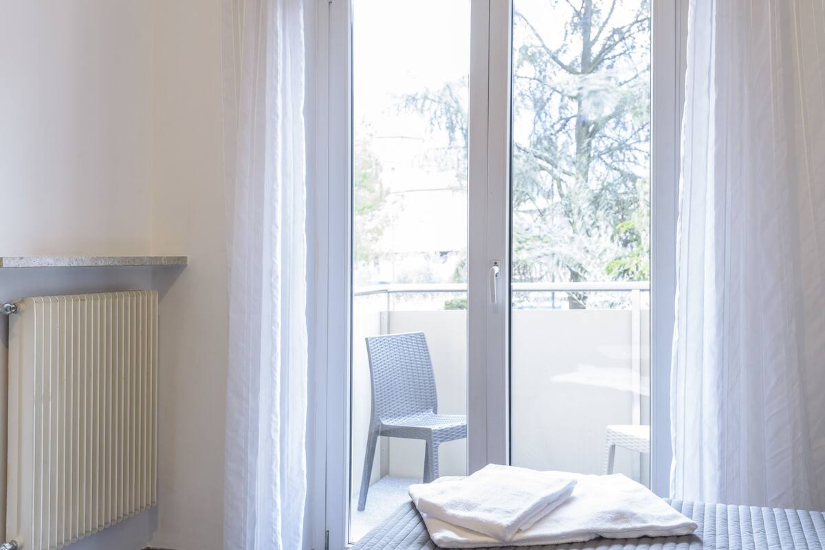 A room with a radiator, a chair, and a bed with a folded towel.