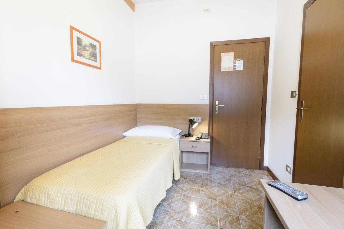 A bedroom with a bed, bedside table, lamp, and a door.