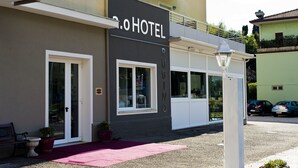 Un hotel con fachada moderna, amplios ventanales y alfombra roja en la entrada.