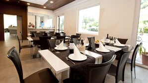 Un restaurante con varias mesas dispuestas para comer, que presenta un interior moderno con paneles de techo de madera y ventanas amplias que dejan entrar luz natural.