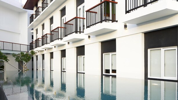 Un hotel moderno con una piscina larga, varios balcones y un diseño contemporáneo y limpio.