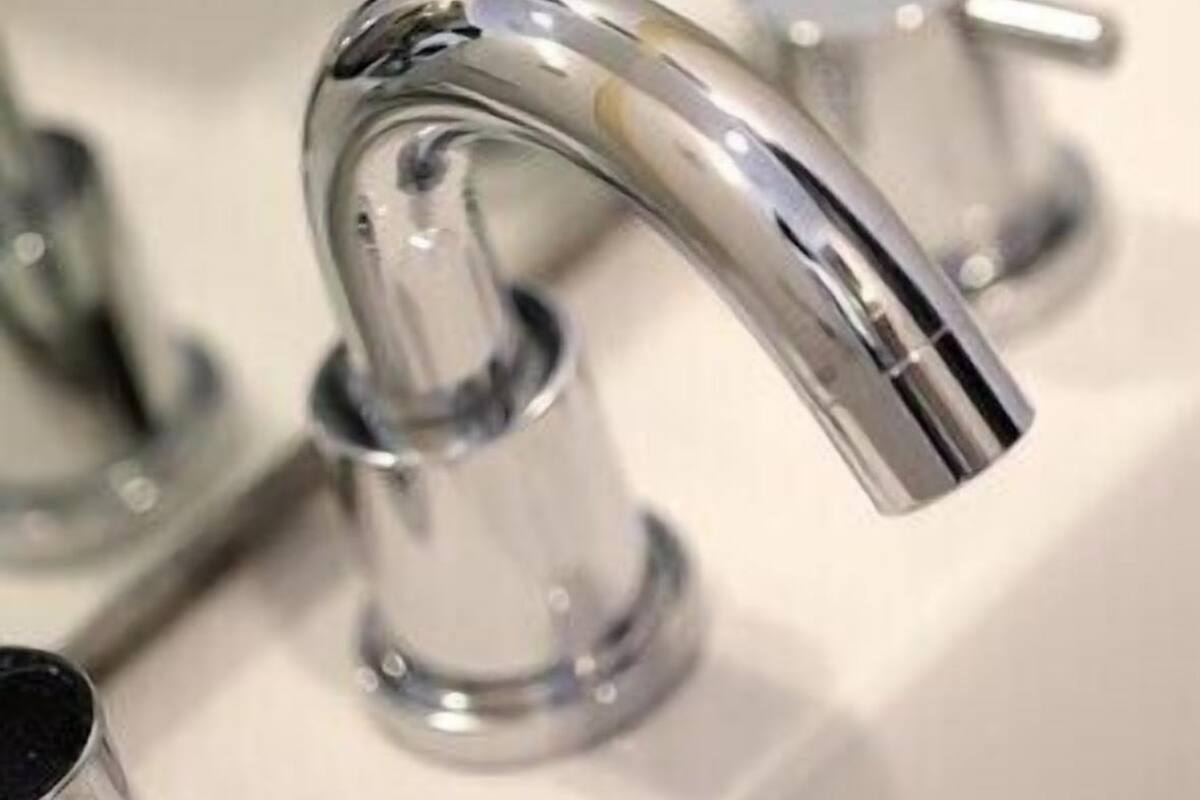 A chrome faucet with a curved spout, a sink, and a drain.