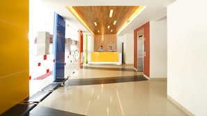 Un vestíbulo moderno con una recepción, techo de madera y pared de vidrio.
